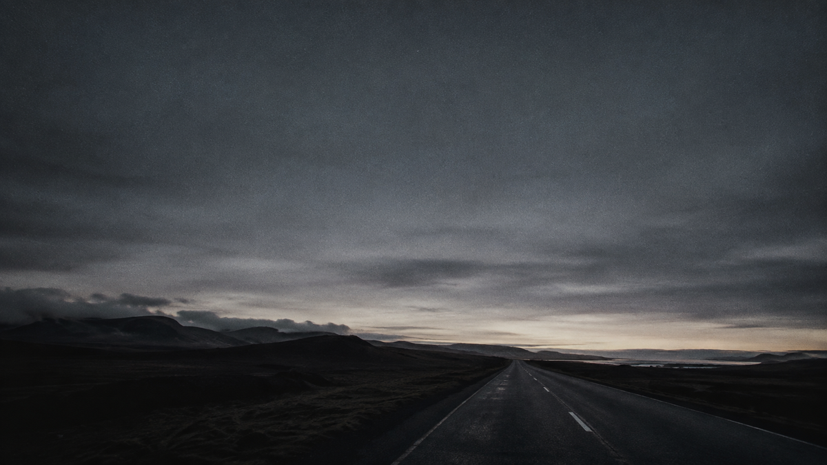 An empty road stretching out under a heavy grey sky